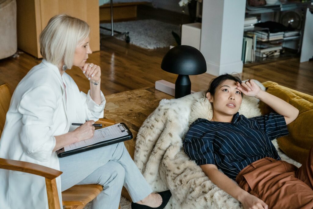 Séance de psychanalyse. La psychanalyste est assise dans un fauteuil et la patiente est allongé sur un canapé.